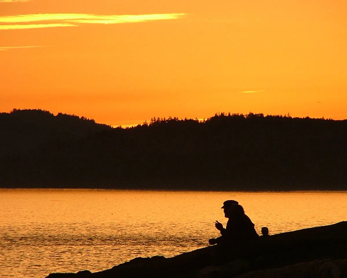 Person sitting on a cliff at sunset