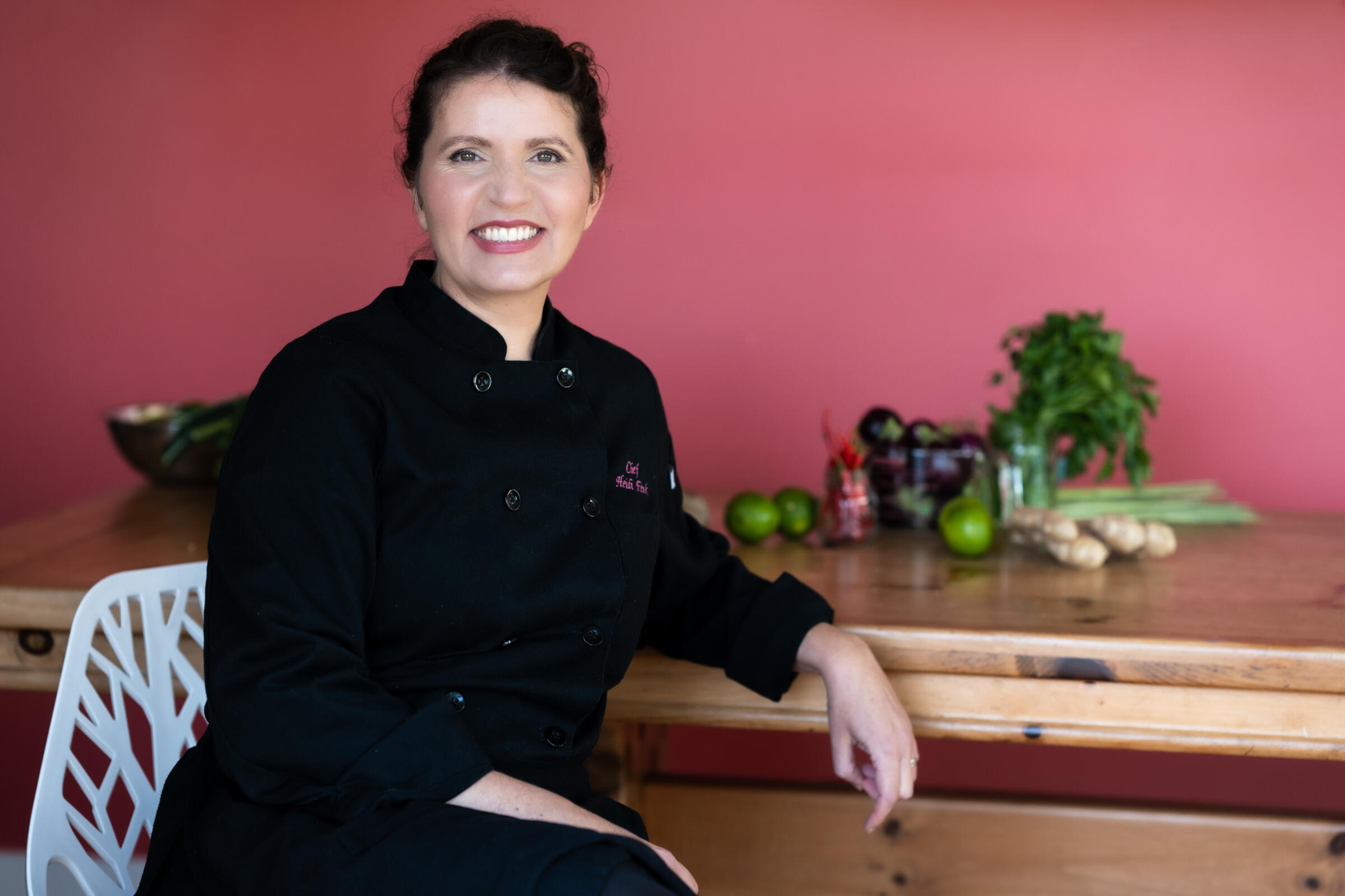 Chef Heidi Fink sits at a counter with fresh produce in the background